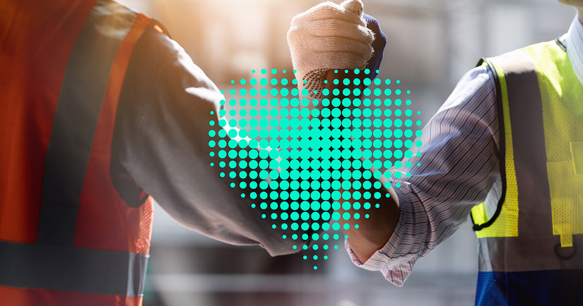 Two men in safety vests are smiling mid-handshake. A gentle beam of sunshine glows through from above and a green heart is hovering in the center of the image.