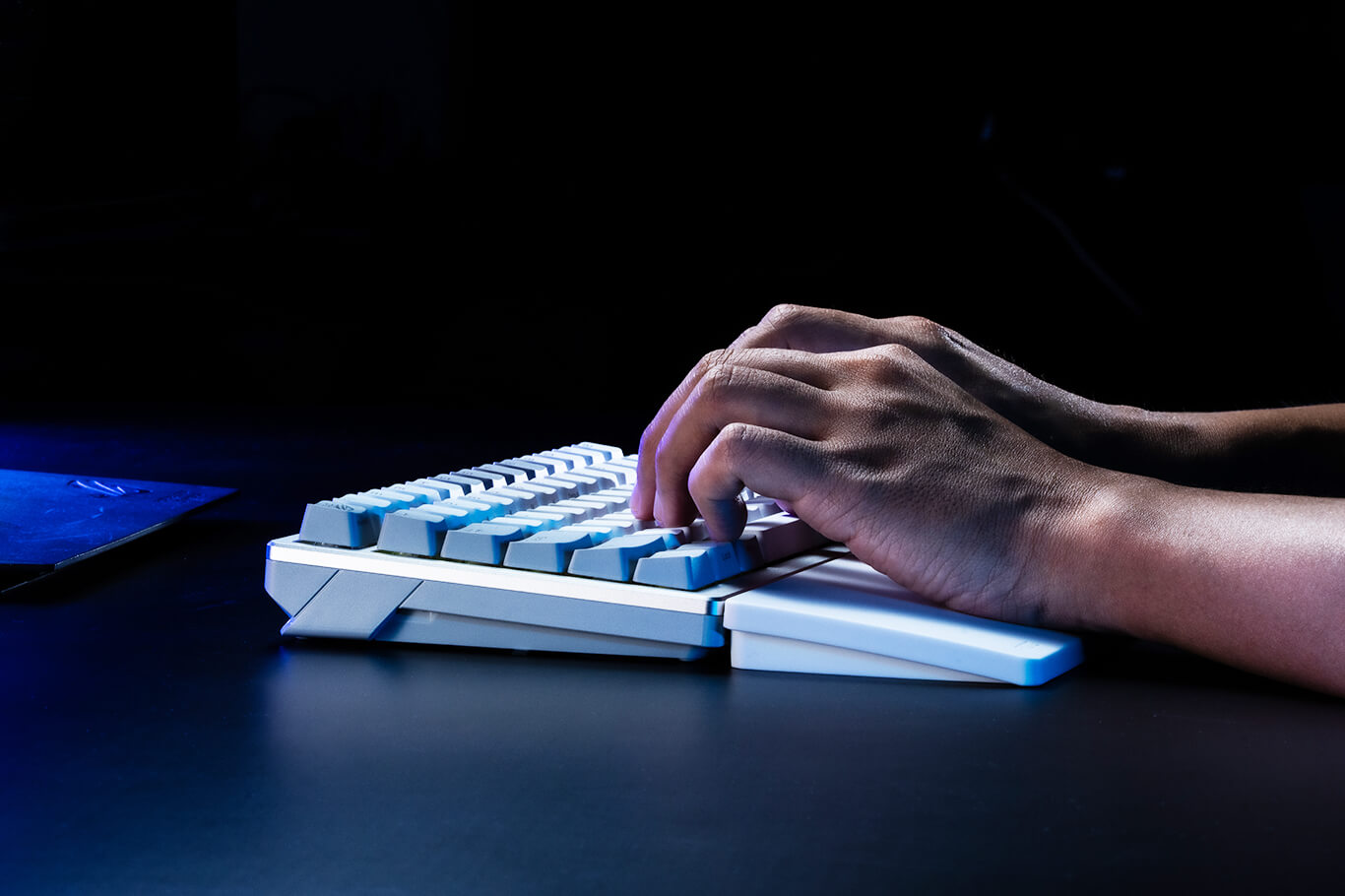 Vista lateral enfocada de alguien apoyando las palmas de las manos en un reposamuñecas blanco de teclado ROG