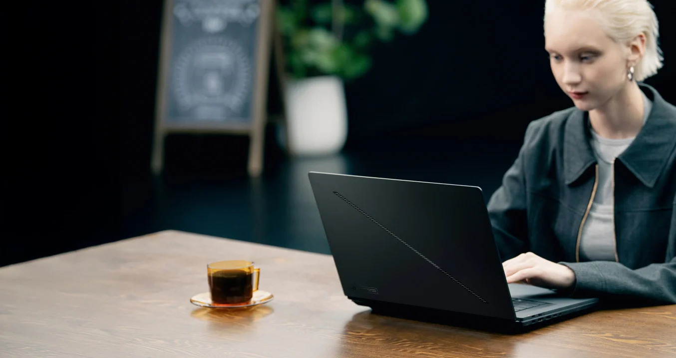 a woman using Zephyrus Duo with the laptop mode in a coffee shop.