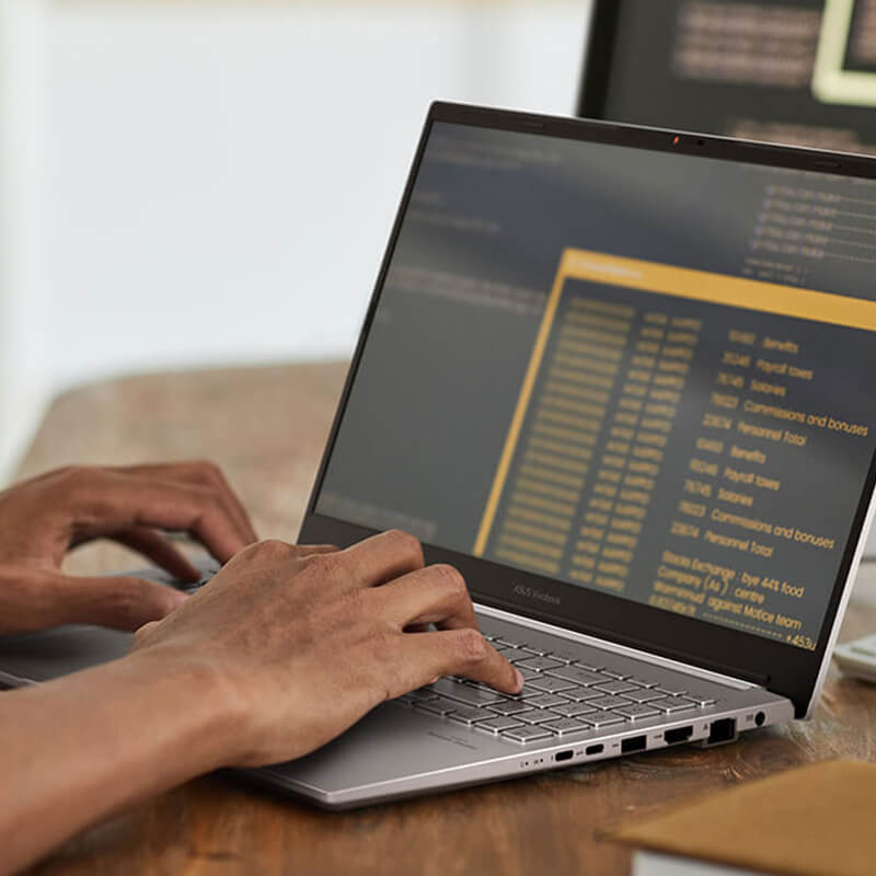 A man using an ASUS laptop and an external display for work.