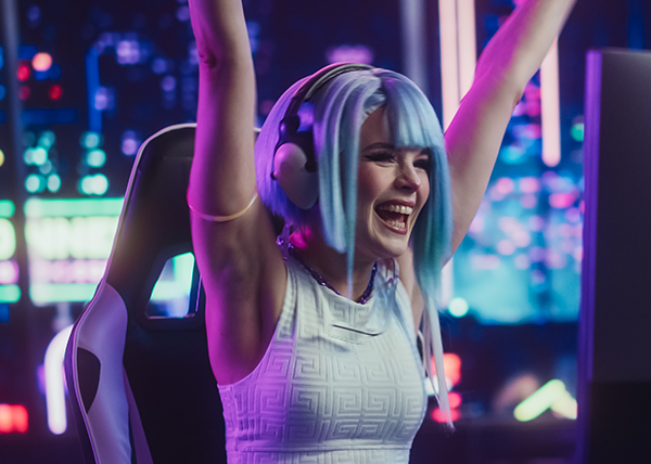 A female gamer cheering in a vibrant gaming setup.