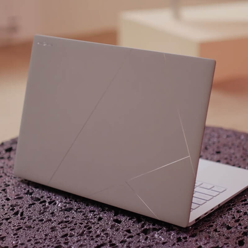Un ASUS Zenbook gris Zumaia se coloca sobre una superficie que tiene una textura similar a la lava.