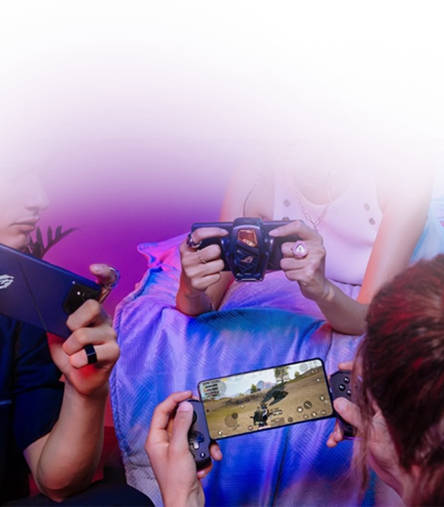 People gaming on ROG Phone with cooler attachment and handheld console showing action game on screen.