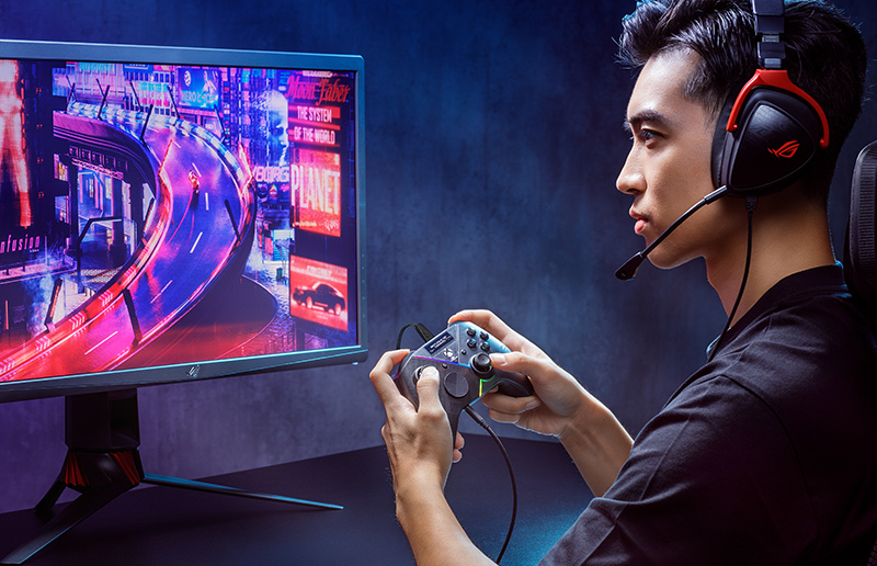 Gamer playing a handheld gaming console in a room with ROG lighting.