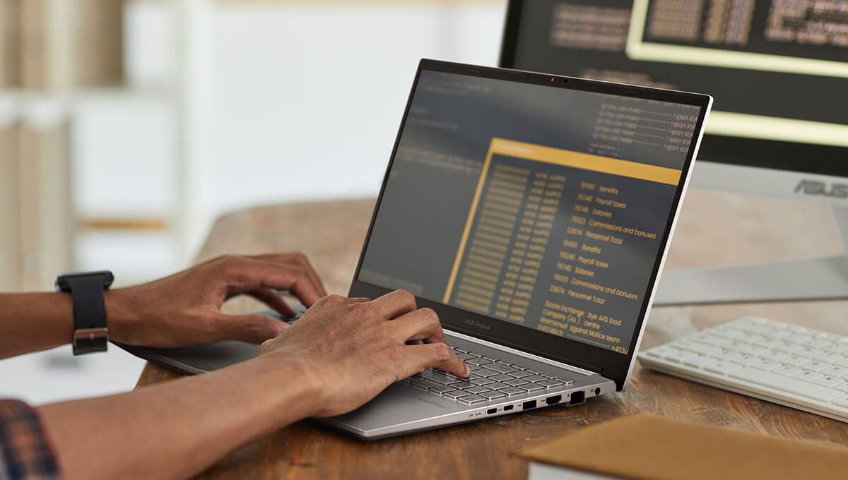 A man using an ASUS laptop and an external display for work.