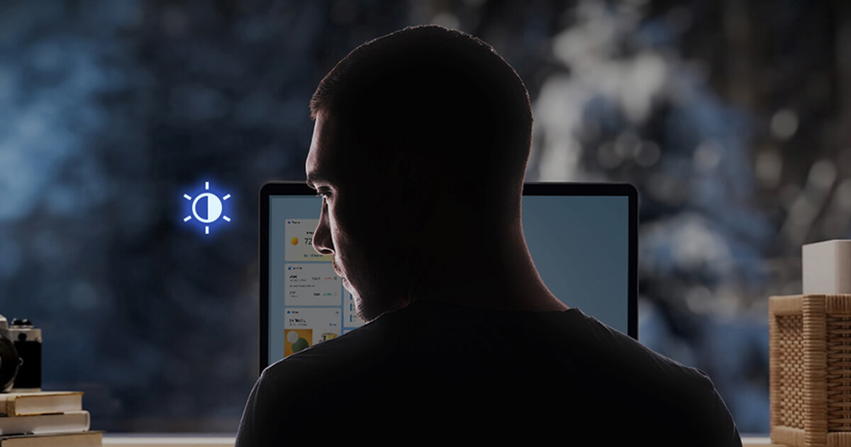 A man is looking away from the laptop screen and the screen is dimmed as a result.