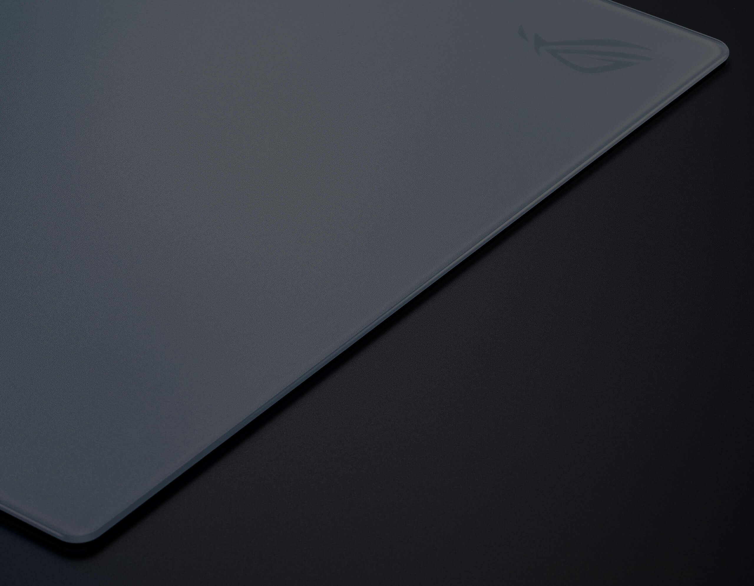An image with a hand turning over a corner of the ROG Hone Ace XXL to show its base material