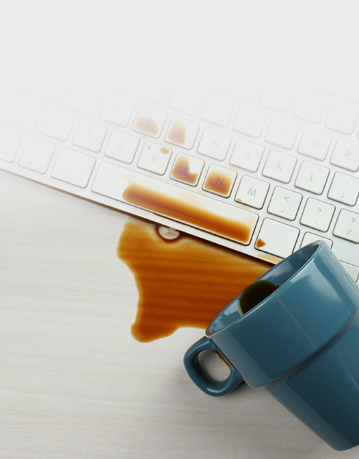 Uma ch&aacute;vena de caf&eacute; entornada num teclado branco