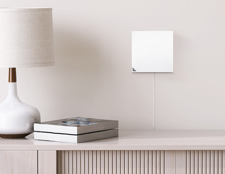 De RT-AX57 Go aan de muur gemonteerd op een schone muur achter een kast.