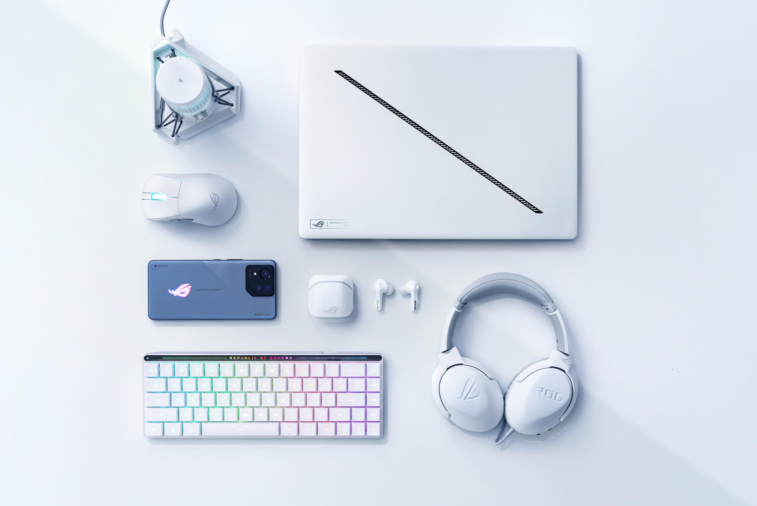 A Platinum White Zephyrus G16, arranged near an ROG mouse, carrying case, and its power adapter.